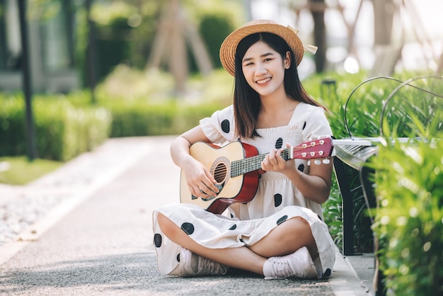 Foto gratuita mujer asiática tocando la guitarra en el concepto de estilo de vida y recreación del parque