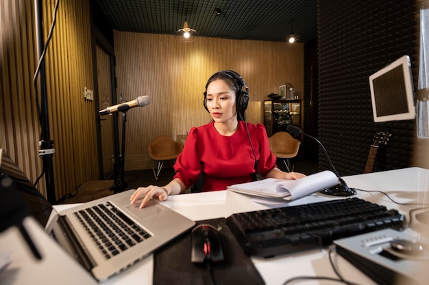Mujer asiática trabajando en radio con equipo profesional