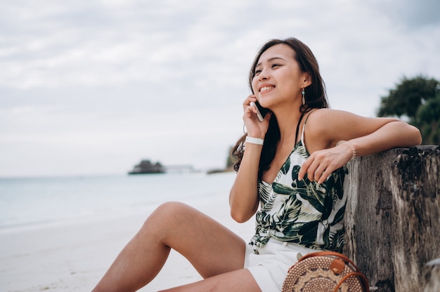 Foto gratuita mujer asiática usin g teléfono en la playa de vacaciones