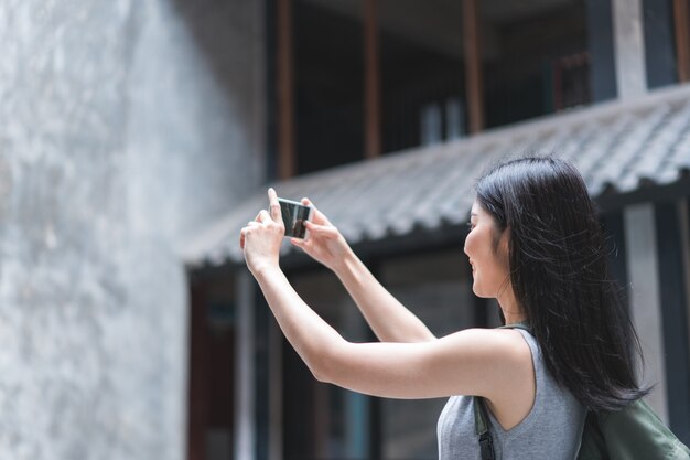 Mujer asiática viajera que usa un teléfono móvil para tomar una foto mientras pasa un viaje de vacaciones a Pekín, China