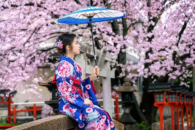 Mujer asiática vistiendo kimono tradicional japonés y flor de cerezo en primavera, templo de Kyoto en Japón.