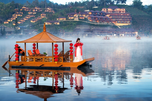 Mujer asiática vistiendo traje tradicional chino en un barco en la aldea tailandesa de Ban Rak, provincia de Mae Hong Son