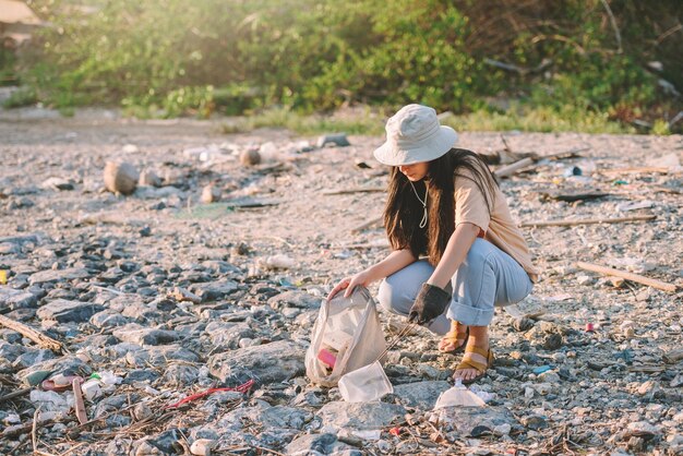 Mujer asiática voluntaria de conservación del medio ambiente ayuda a mantener y limpiar basura de plástico y espuma en la playa y el área del parque Voluntariado día mundial del medio ambiente