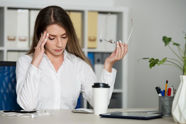 Mujer con aspecto cansado en el trabajo debido al tiempo que pasa en el teléfono