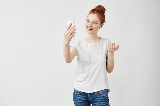 Mujer astuta alegre que sonríe hablando en el teléfono en auriculares.