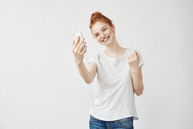 Mujer astuta alegre que sonríe hablando en el teléfono en auriculares.