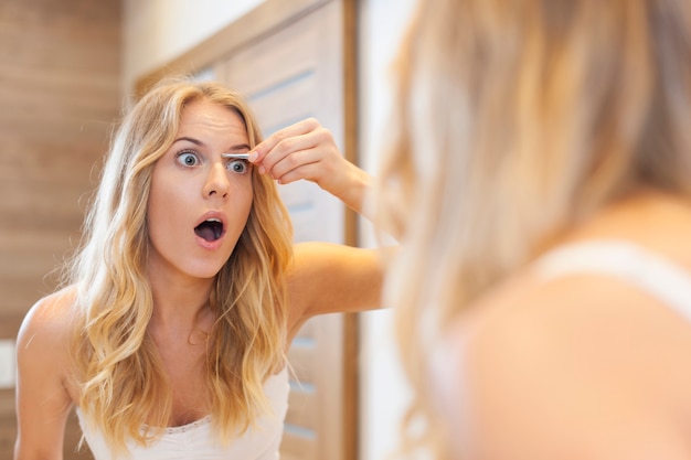 Foto gratuita mujer asustada depilarse las cejas en el baño.