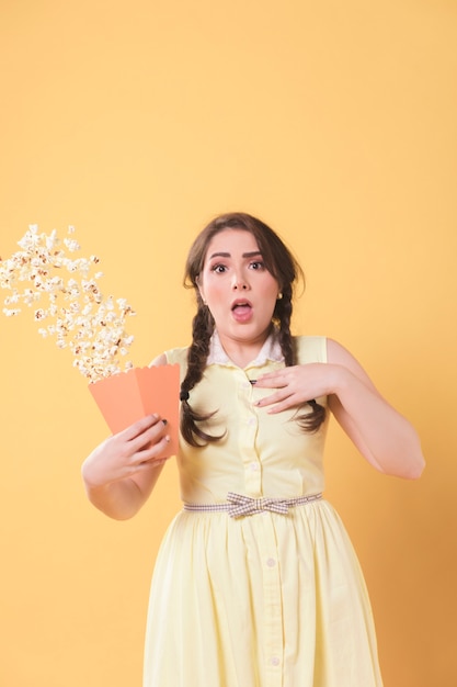 Mujer asustada posando mientras derrama palomitas de maíz