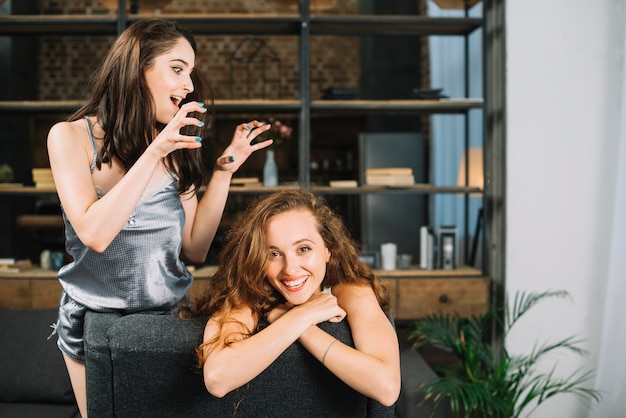 Mujer asustando a su amiga apoyándose en la silla