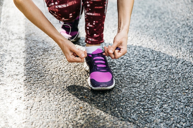 Mujer atando zapatos de correr en calle