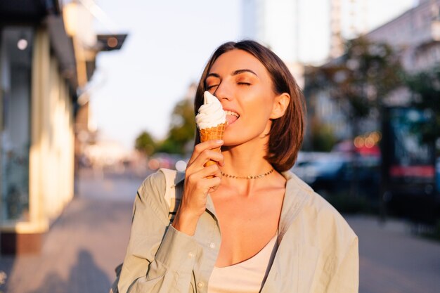 Mujer en el atardecer de verano con helado en las calles de la ciudad