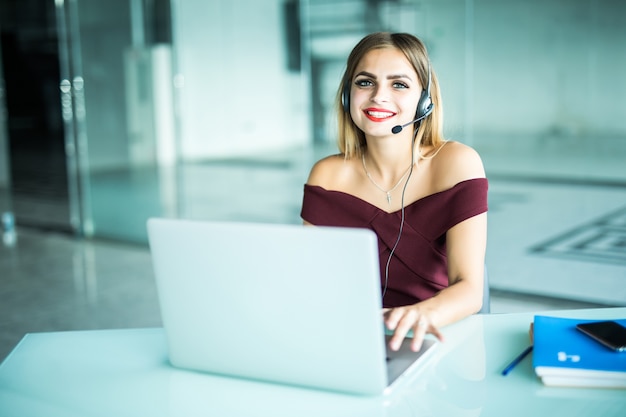 Foto gratuita mujer atenta enfocada en auriculares se sienta en el escritorio con computadora portátil, mira la pantalla, toma notas, aprende idiomas extranjeros en internet, autoeducación del curso de estudio en línea en la web consulta al cliente por video