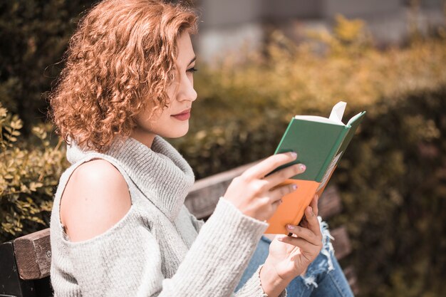 Mujer atentamente leyendo el libro en el parque