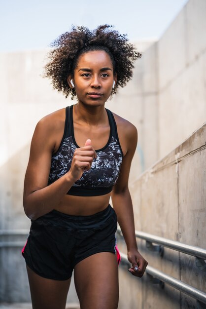 Mujer atlética afro corriendo y haciendo ejercicio al aire libre