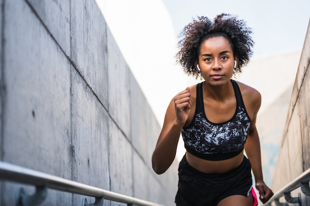 Mujer atlética afro corriendo y haciendo ejercicio al aire libre