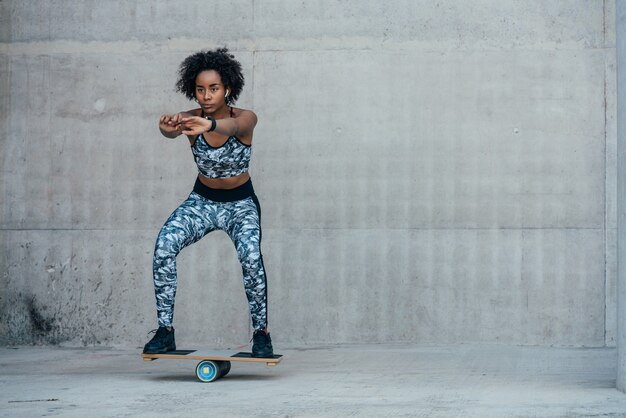 Mujer atlética afro hacer ejercicio y hacer la pierna en cuclillas al aire libre. Concepto de deporte y estilo de vida saludable.