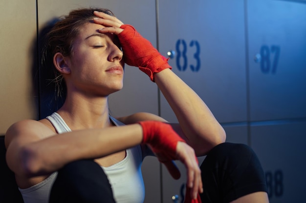 Mujer atlética agotada descansando con los ojos cerrados en un vestuario después del entrenamientoxA