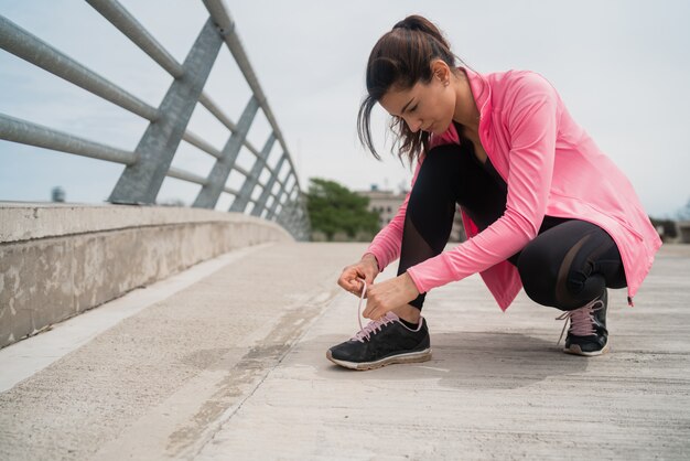 Mujer atlética atarse los cordones de los zapatos