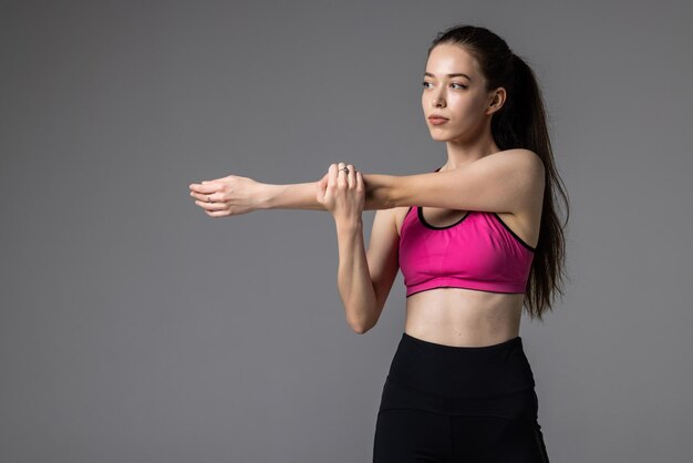 Mujer atlética estirando la mano sobre el gris