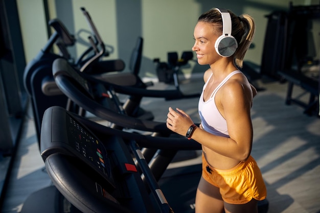 Mujer atlética feliz con auriculares para correr en la pista de atletismo en un gimnasio