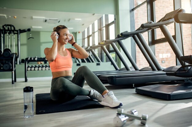 Mujer atlética feliz escuchando música con auriculares en un gimnasio