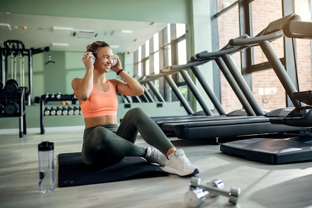 Mujer atlética feliz escuchando música con auriculares en un gimnasio