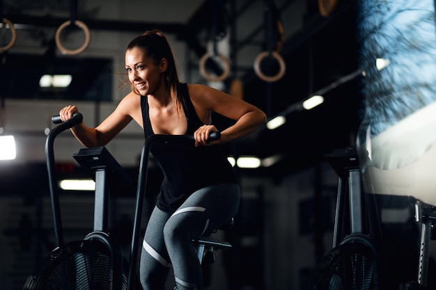 Mujer atlética joven en bicicleta estática mientras entrena en un gimnasio