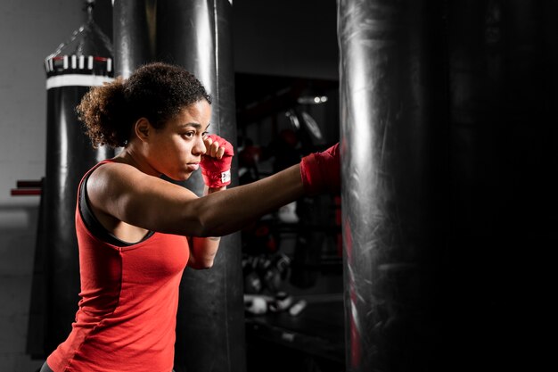 Mujer atlética lateralmente entrenando en el centro de boxeo