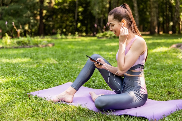 Mujer atlética en ropa deportiva está mirando en la pantalla del teléfono celular