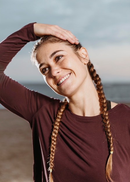 Foto gratuita mujer atlética sonriente que se extiende por la playa