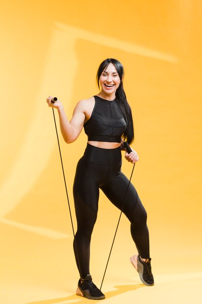 Mujer atlética sonriente en traje de gimnasio con saltar la cuerda