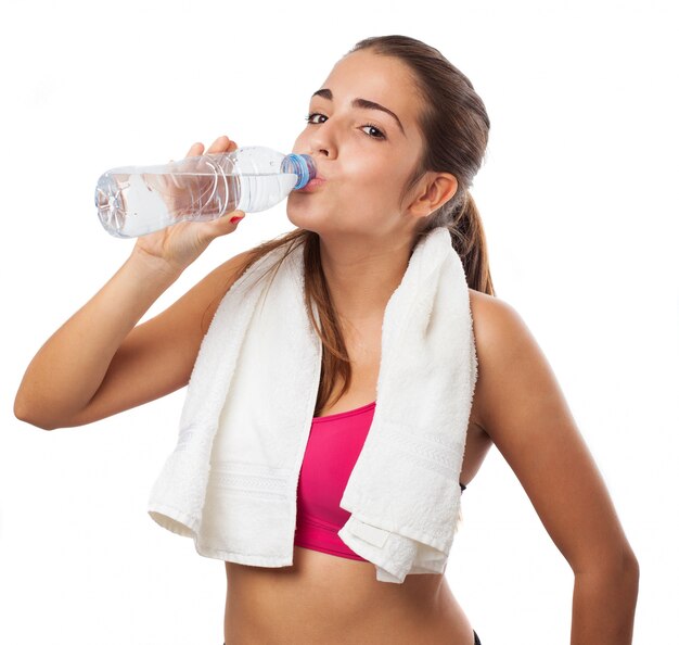 Mujer atlética con una toalla y bebiendo agua