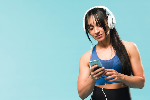 Mujer atlética en traje de gimnasio escuchando música en auriculares