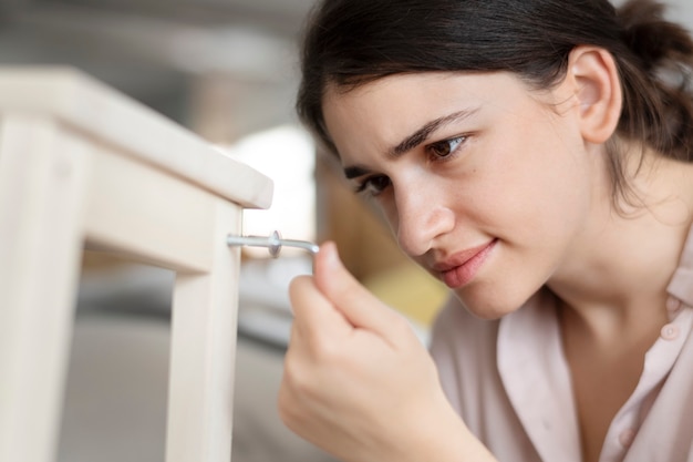 Mujer atornillando la uña de la silla para muebles listos para ensamblar