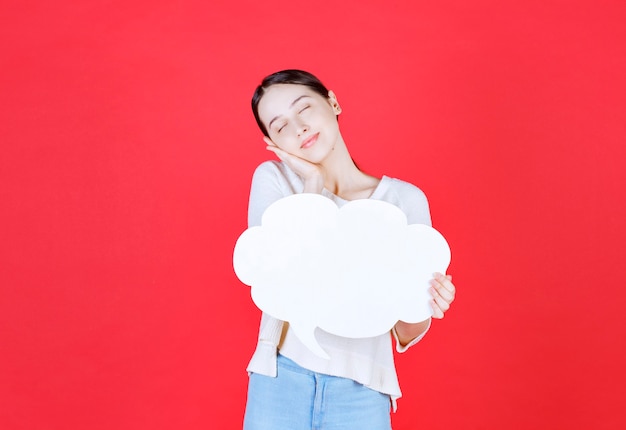 Mujer atractiva alegre sosteniendo el bocadillo de diálogo con forma de nube