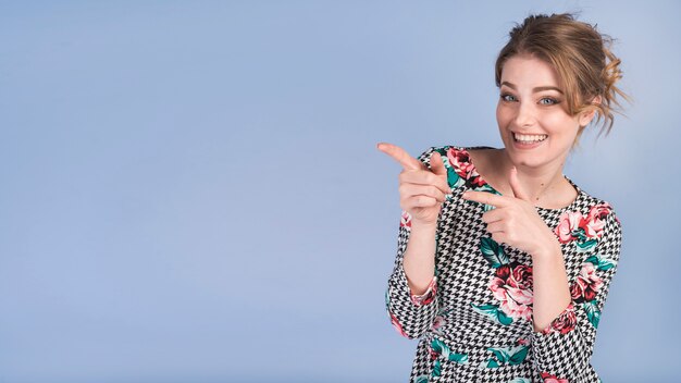 Mujer atractiva alegre en vestido elegante que señala en el lado