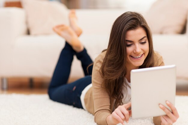 Mujer atractiva en la alfombra con tableta digital