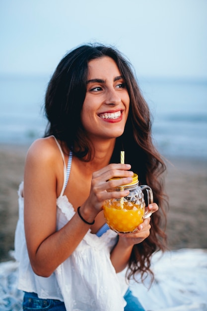Mujer atractiva con bebida en la playa
