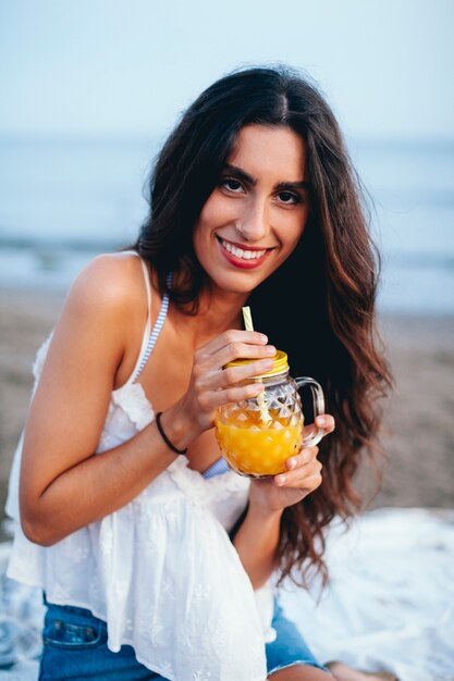 Mujer atractiva con bebida tropical en la playa