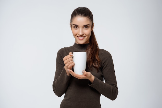 Mujer atractiva bebiendo té, sosteniendo la taza