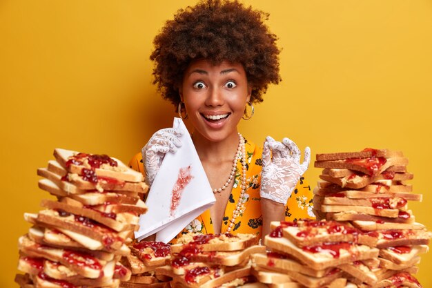 Mujer atractiva con cabello afro rodeado de sándwiches de gelatina de mantequilla de maní