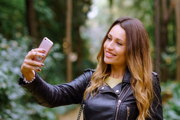 Mujer atractiva con una cara feliz tomando una selfie en el teléfono