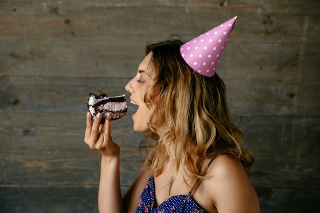 Mujer atractiva comiendo un pastel de chocolate crema, celebrando la fiesta de cumpleaños