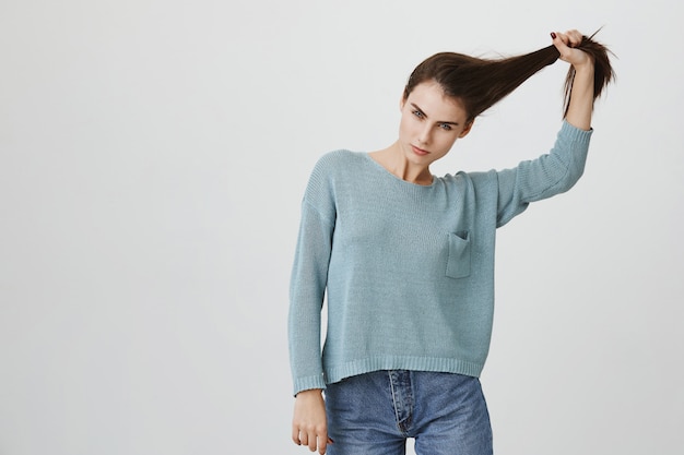Foto gratuita mujer atractiva descarada que tira del pelo, anuncia productos para el cuidado del cabello