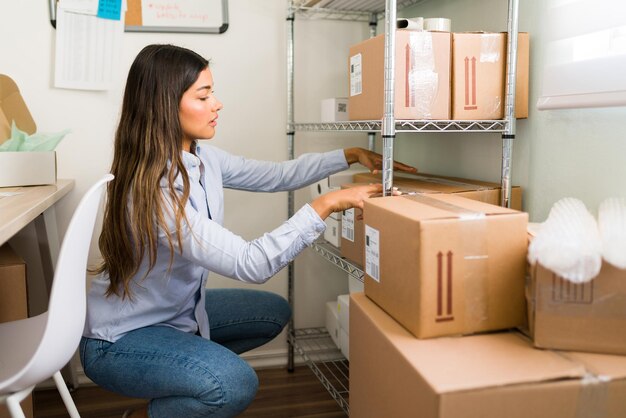 Mujer atractiva y dueña de un negocio que organiza muchos paquetes y cajas listas para enviar a los clientes desde la tienda comercial en línea