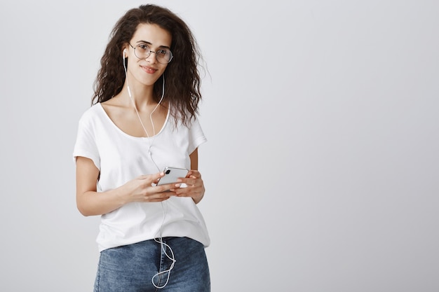 Foto gratuita mujer atractiva escuchando música en auriculares y mensajería a través del teléfono móvil