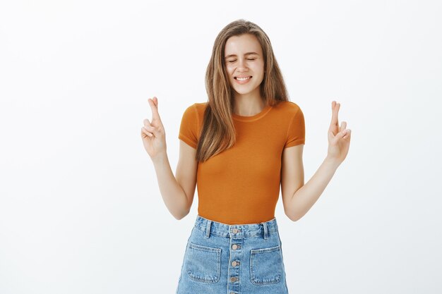 Mujer atractiva esperanzada que desea. Chica esperando que el sueño se haga realidad. Estudiante deseando, esperando buena fortuna