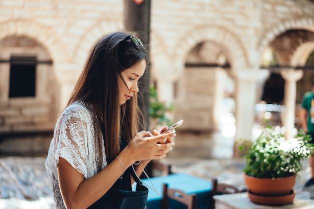 Mujer atractiva está de pie con el teléfono. La niña está escribiendo un mensaje.