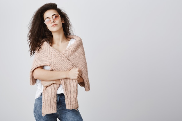 Mujer atractiva con estilo en gafas de sol y un suéter mirando descarado