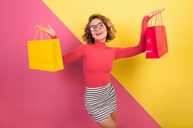 Mujer atractiva excitada en elegante traje colorido con bolsas de la compra.